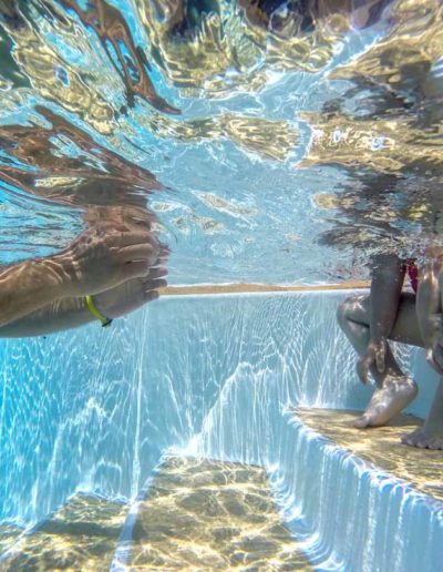 Parent et enfant sur les marches piscine extérieure